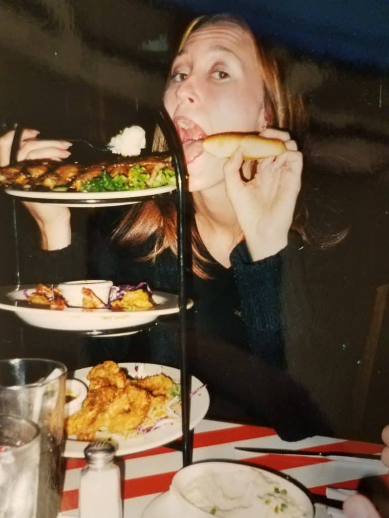 Collage age woman posing with a tower of food.