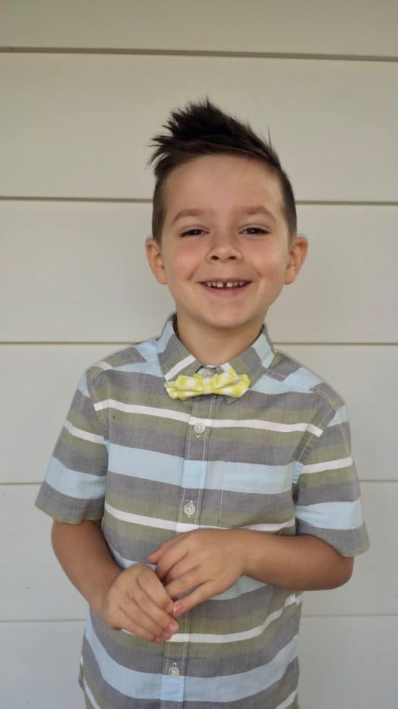 Young caucasian boy, about 6 years old, in stripe button up short sleeve shirt and bow tie, smiling for the camera.