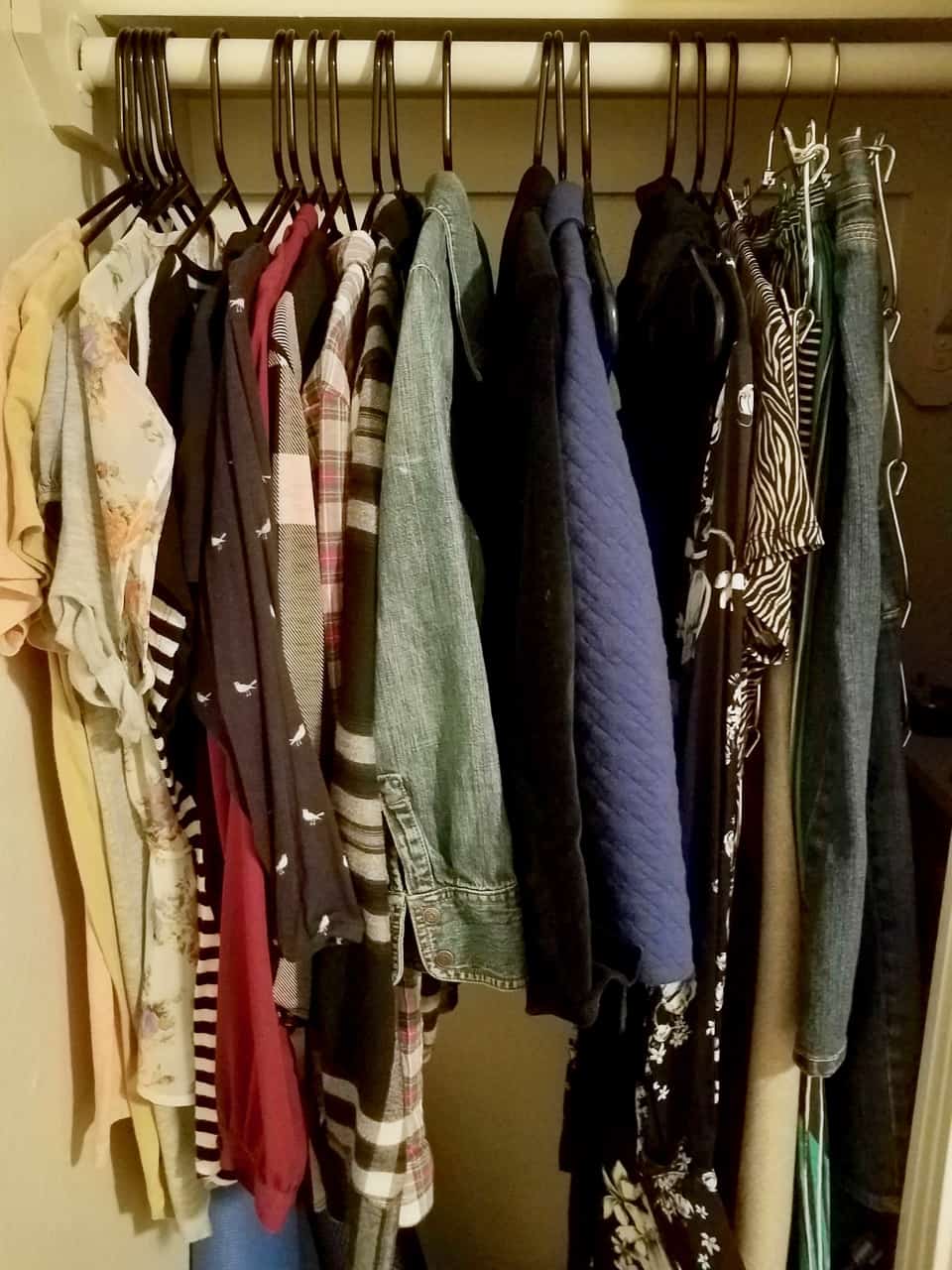 One small rack of clothes hanging in a closet.