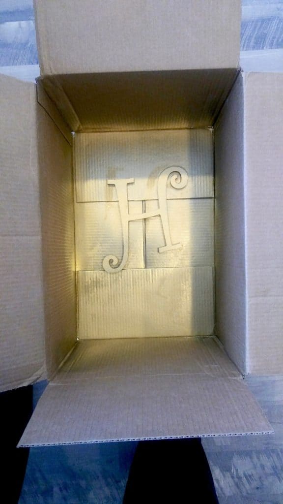 the letter h form sitting in a cardboard box after being spray painted gold.