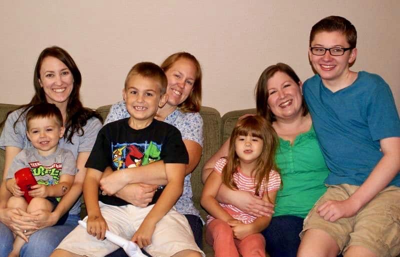 Family Photo of three sisters ranging from 30-40 years with 3 younger boys and one young girl sitting on laps.