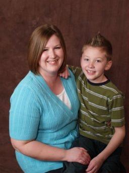 Caucasian woman in her 30's wearing a light blue shirt with a young, caucasian boy sitting on her lap.