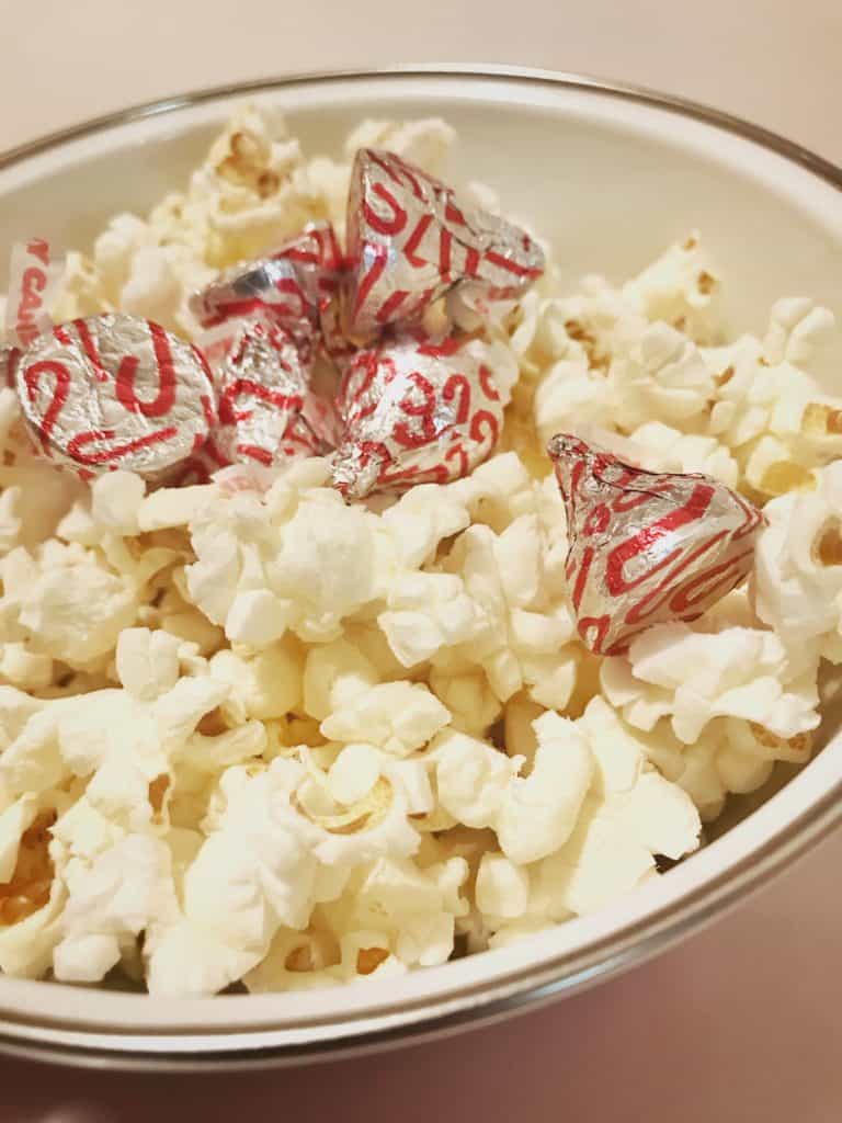 Bowl of popcorn with wrapped holiday Kisses sitting on top of the popcorn