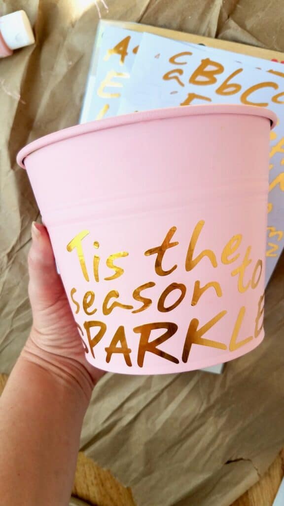 Paint a dollar store bucket pink and use stickers to spell out "Tis the season to sparkle" for a girl's bedroom Christmas tree.