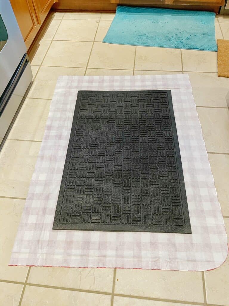 Cut out the fabric or table cloth with an excess of 6 inches around the black mat. You want enough extra fabric to wrap around your black mat.