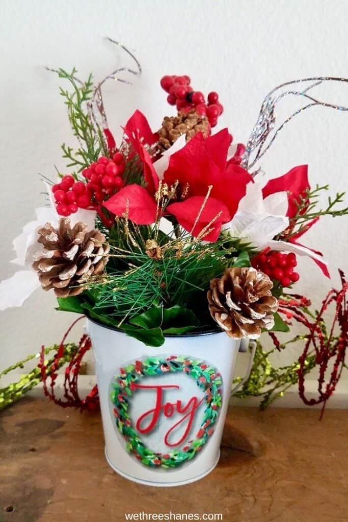 Learn how to make this cheerful Christmas Floral Arrangement using Dollar Tree supplies. An easy Christmas decor craft! | We Three Shanes