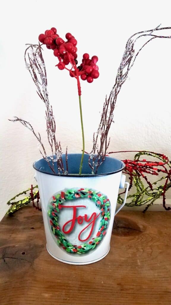 Christmas bucket with floral foam. Two glittery sticks are on each side and red berries are in the middle.