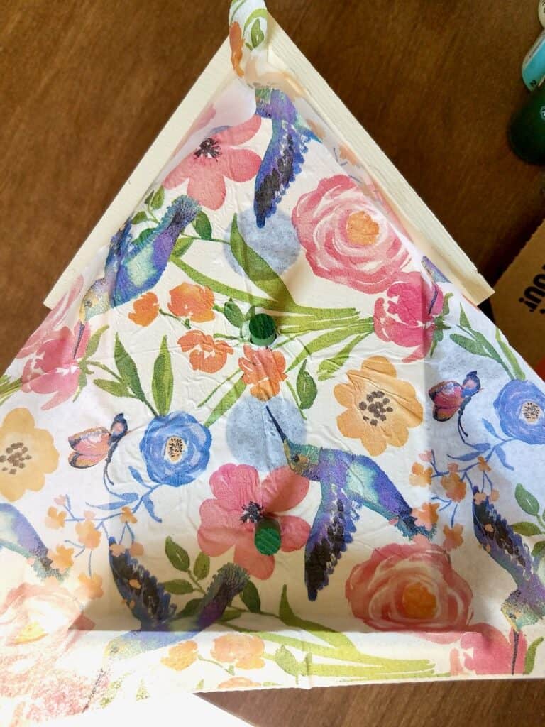 The garden theme napkin is slid on top of the mod podged birdhouse with the perches sticking up through the napkin.