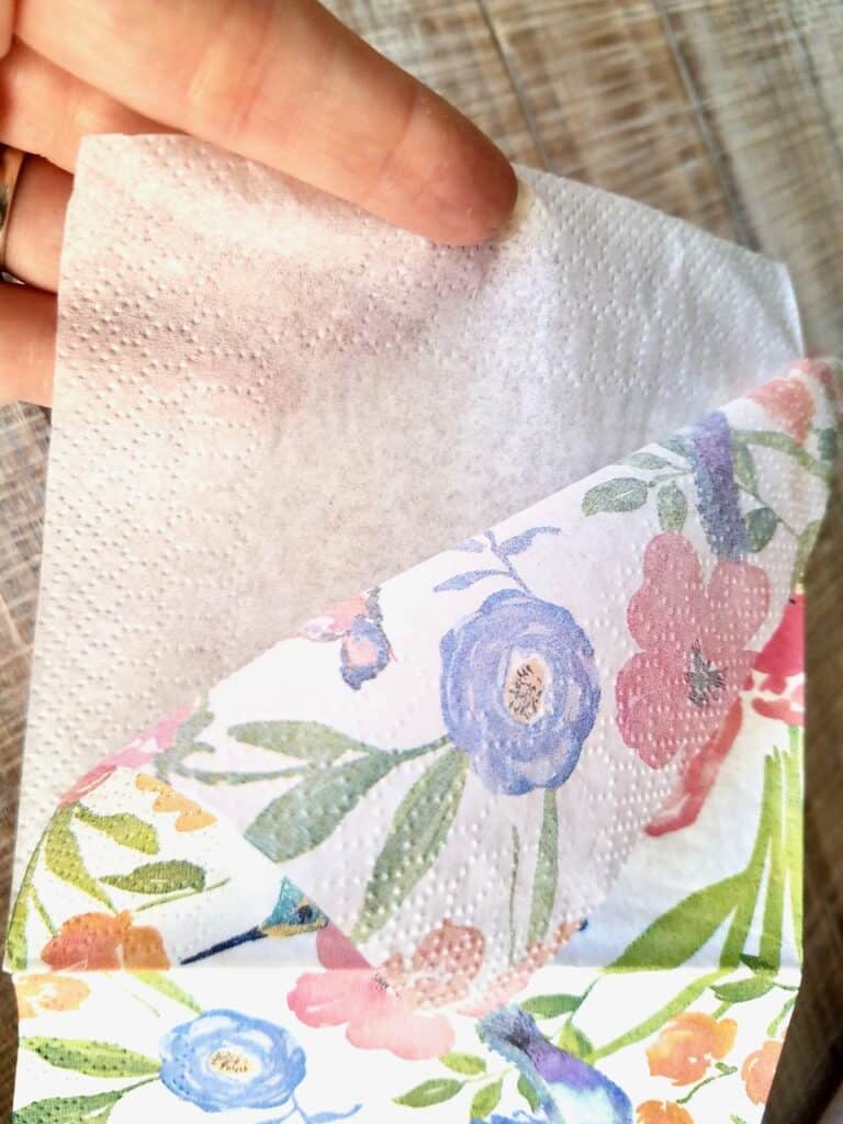 Finger's are pulling the layers of the napkin apart so you're left with one layer of napkin to decoupage with.