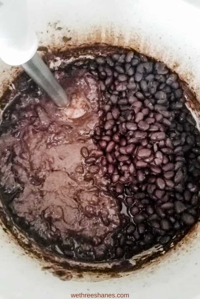 Using a immersion blender to blend about half of the cooked black beans giving them a refried bean consistency. 