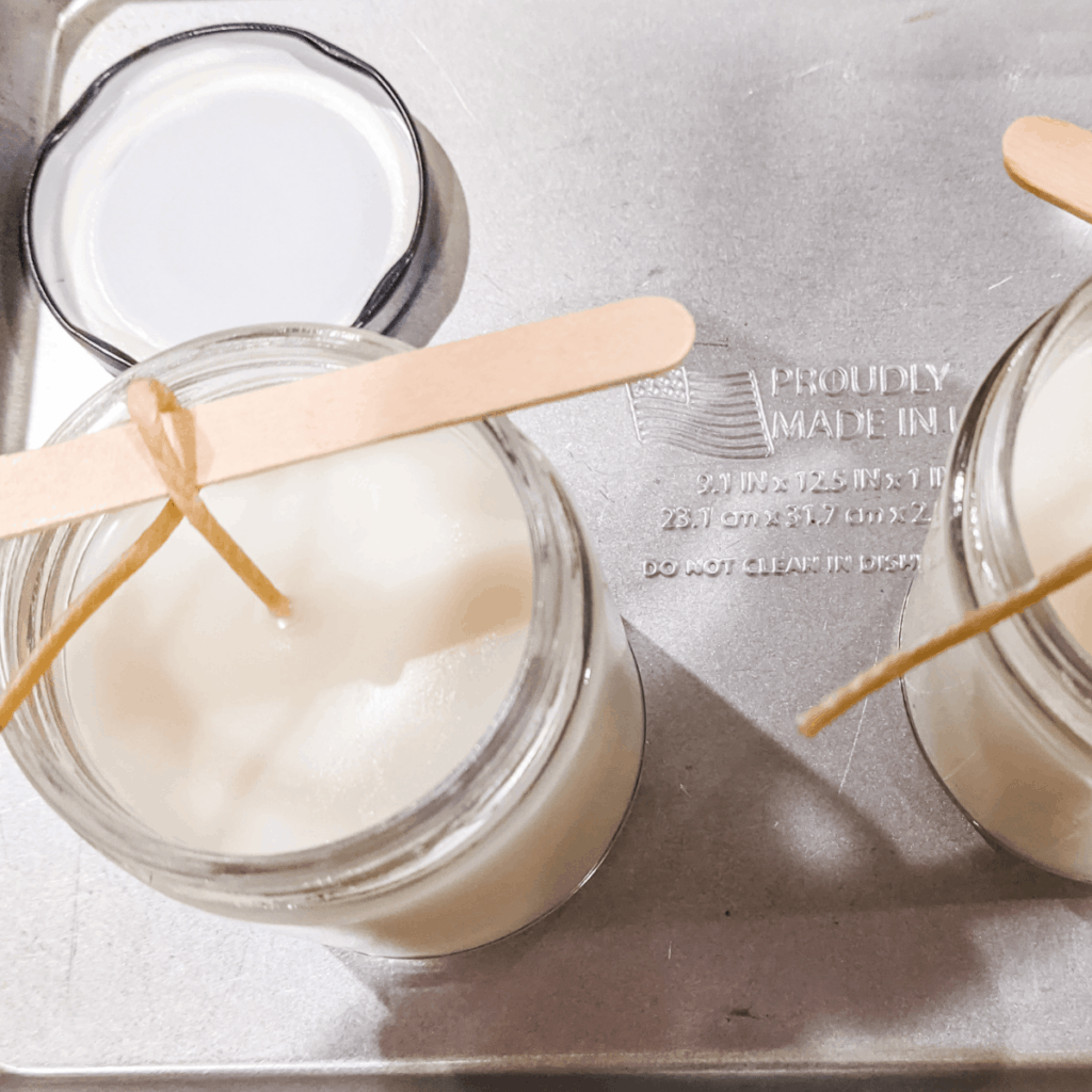 white, soy candles in glass jars cooling before trimming wicks