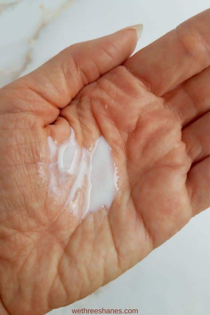 2 pumps of the milk cleanser in a hand. The cleanser is a thin, white liquid.