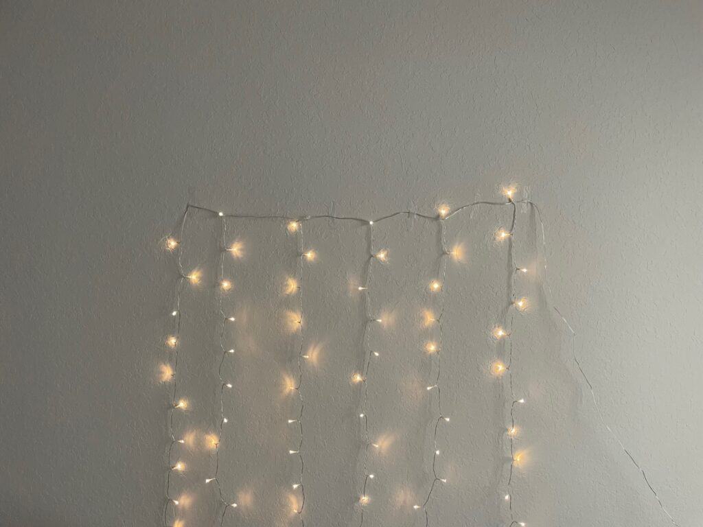 A string of white Christmas lights taped to a wall.