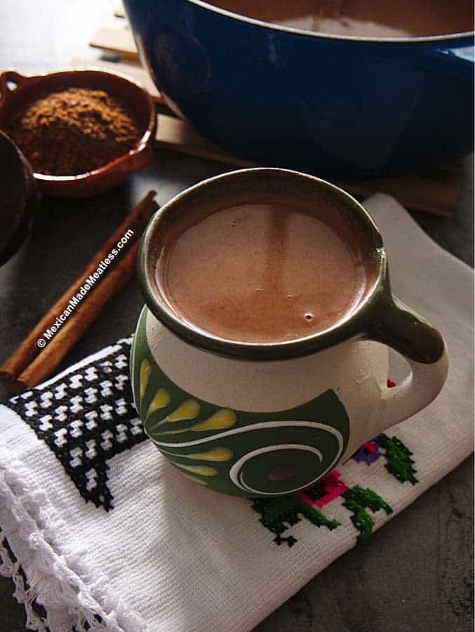 Thick choclate drink in a ceramic Mexican mug sitting on a folded white towel.