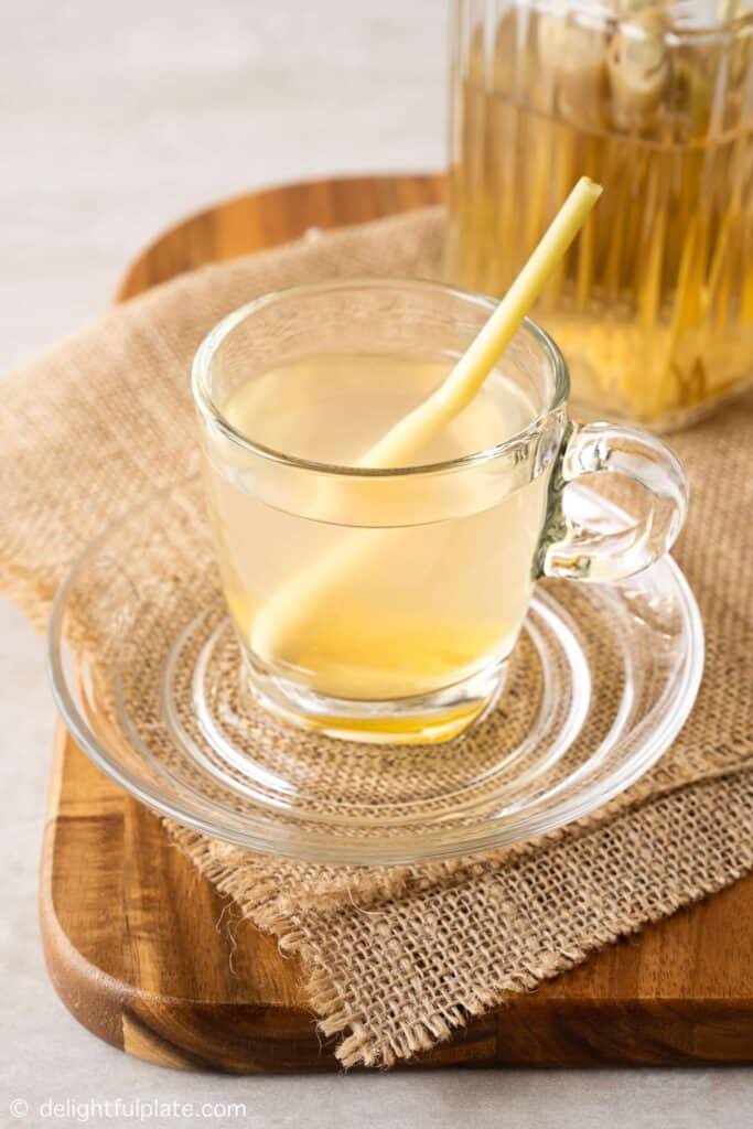 Clear yellow tea in a clear mug with a little spoon sticking out.