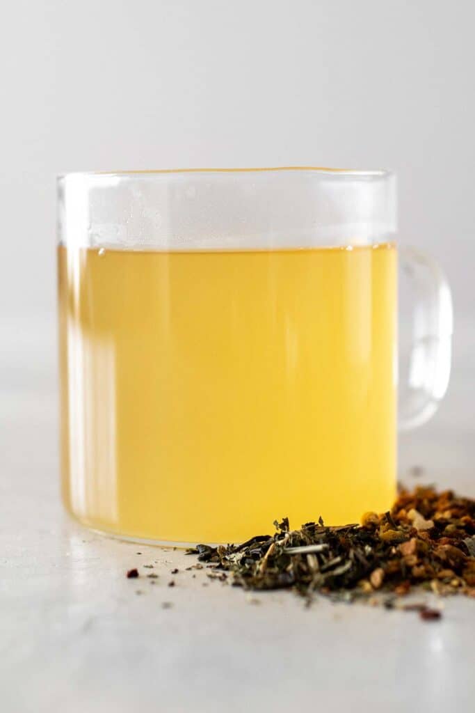 Clear mug full of a bright yellow drink,  known as medicine ball tea.