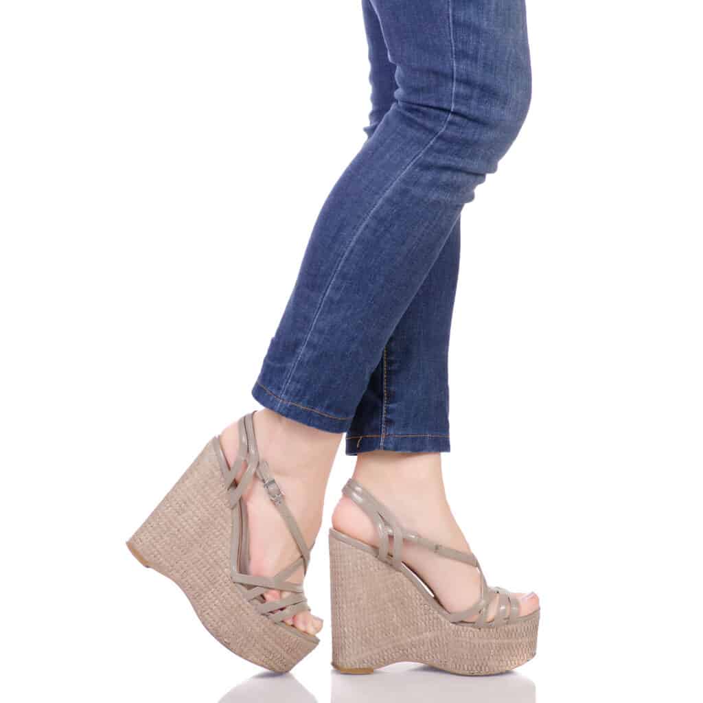 From the knee down - woman wearing jeans and wedge sandals.