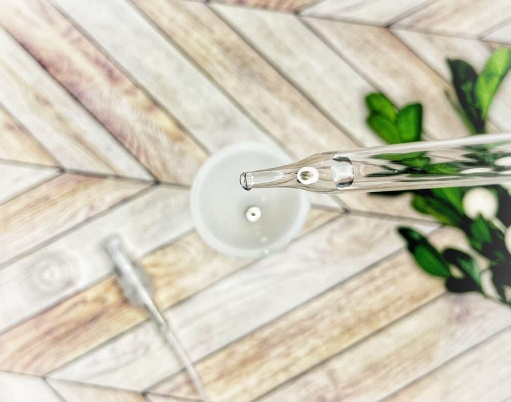 Picture of a glass dropper about to drop some essential oils into a small funnel 