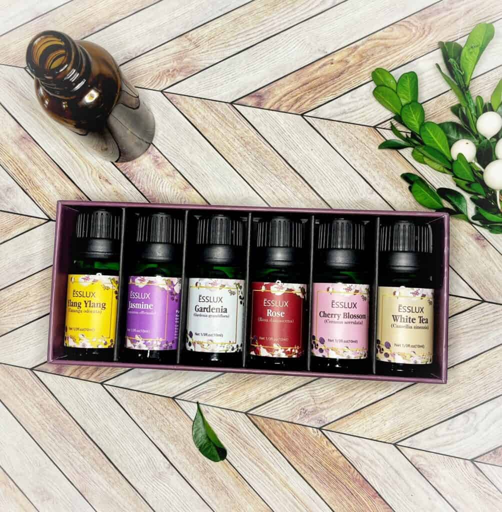 picture of a set of essential oils in a box on a piece of decorative wood.  There is an amber glass bottle to the left and some small leaves to the right | WeThreeShanes