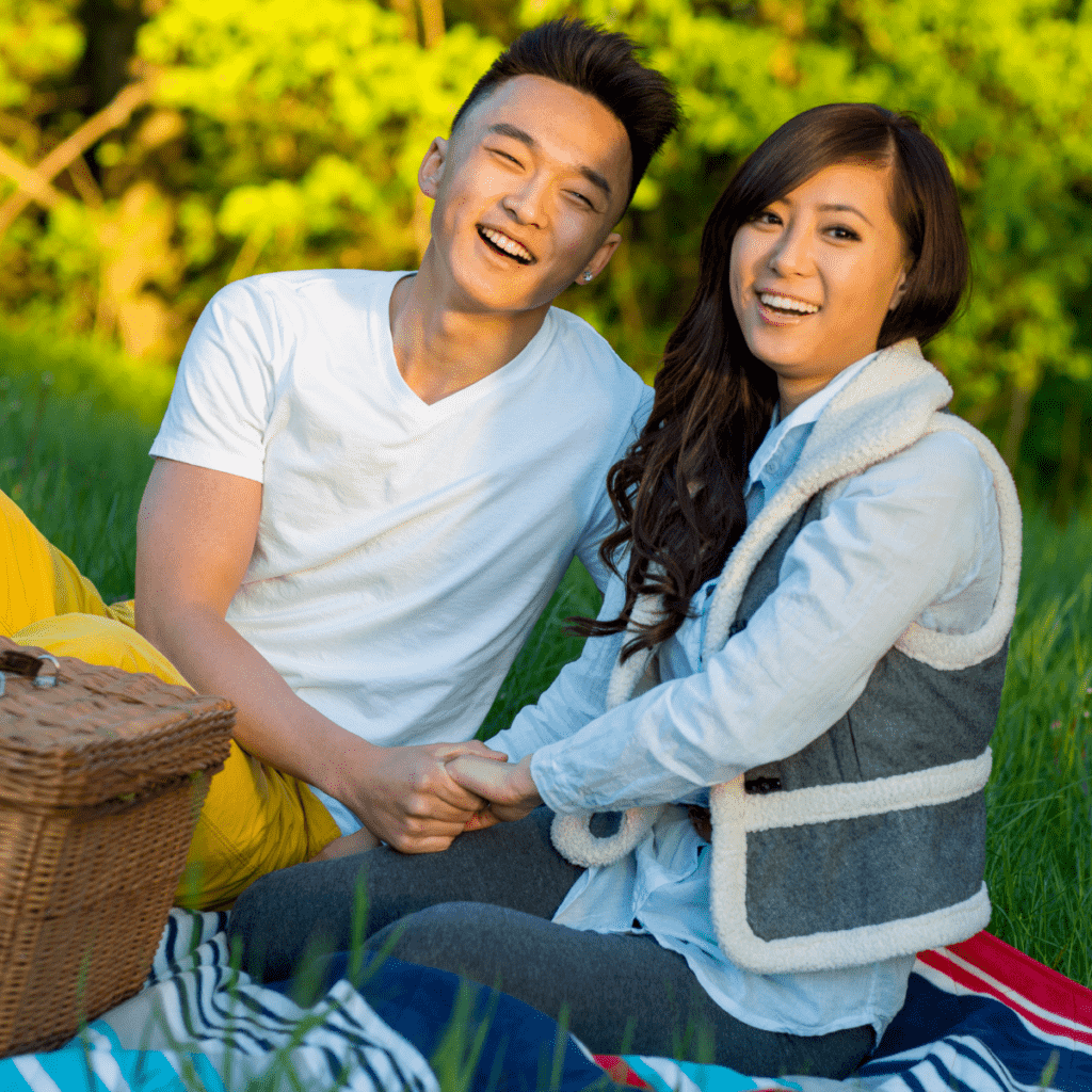 Asian couple holding hands while on a picnic.