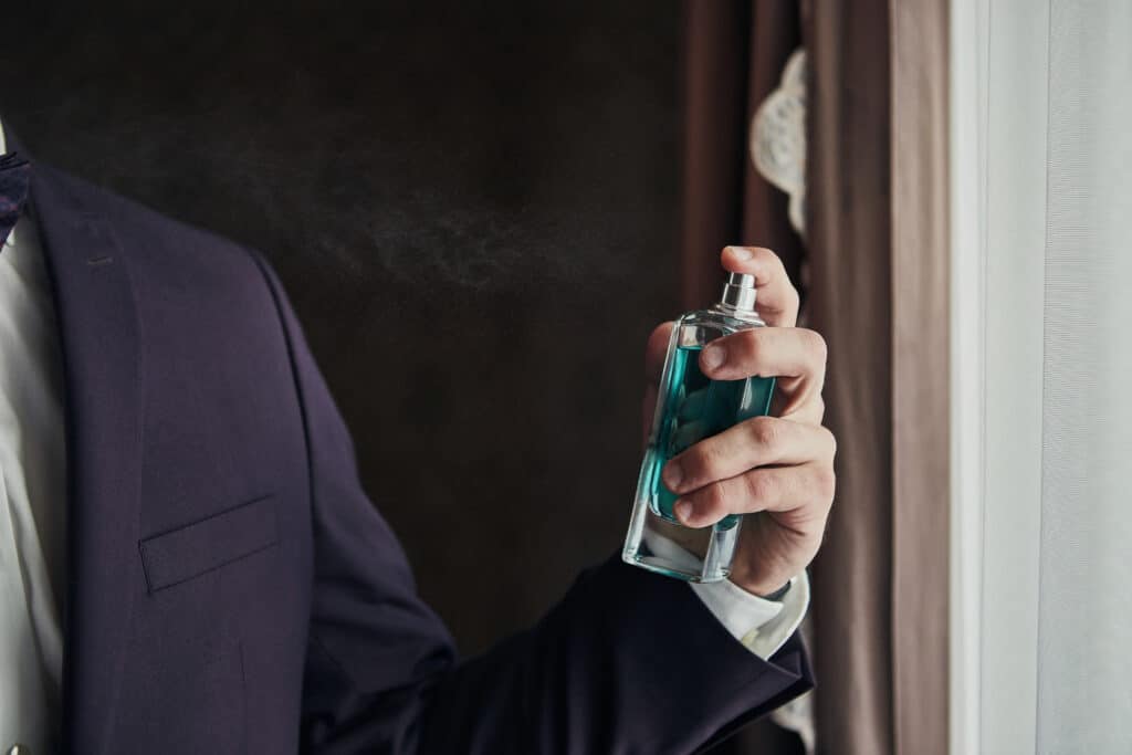 Man in suit spraying himself with cologne