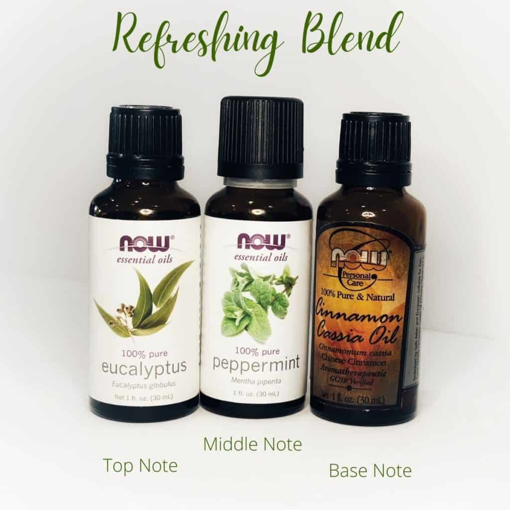 picture of three essential oil bottles.  From left to right, Eucalyptus, peppermint and cinnamon.  Top texts reads Refreshing blend.  Bottom text from left to right reads Top note, middle note and base note | WeThreeShanes 