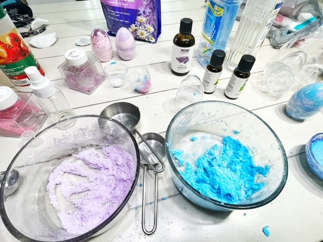 Picture of a kitchen table filled with glass bowls, measuring cups, essential oils and a few other ingredients. | wethreeshanes 