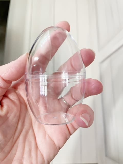 picture of a hand holding up a clear, plastic, egg shaped bath bomb mold | wethreeshanes