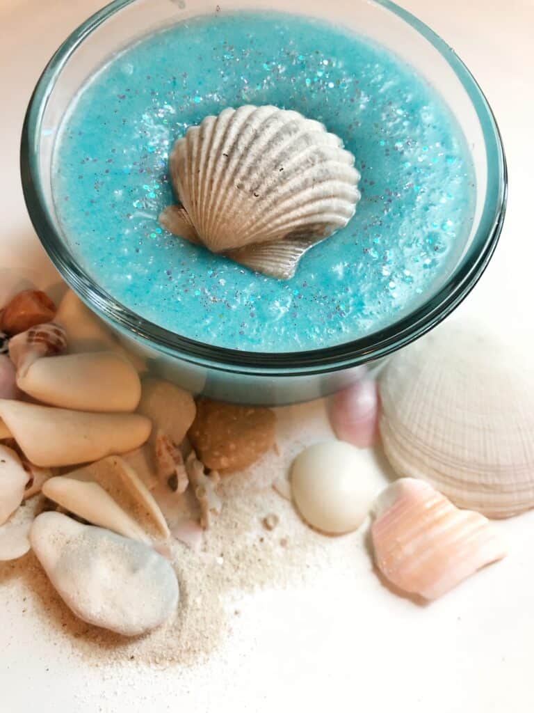 blue sugar scrub with sea shells and sand all around it 