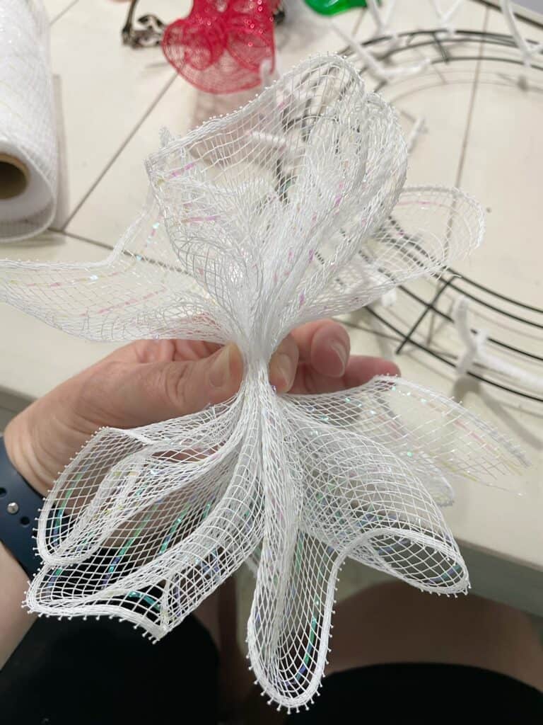 A hand holding white mesh for wreaths scrunched up in a bunch 