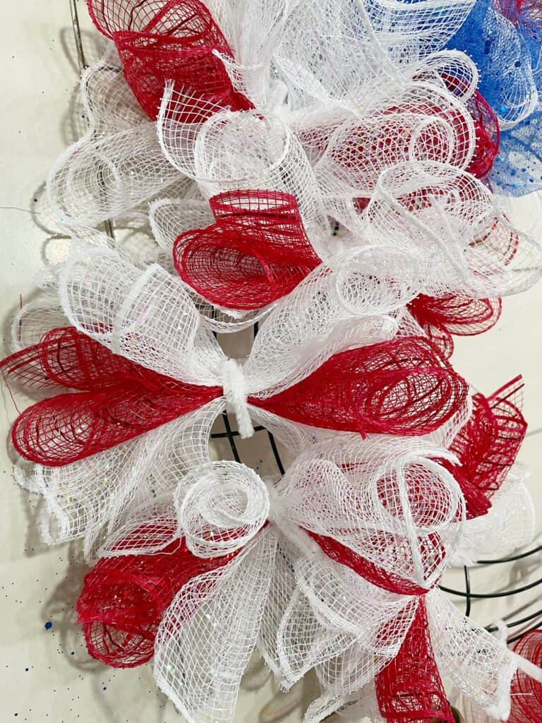 unclose picture of wreath with several sections of mesh clusters twisted onto the wreath form