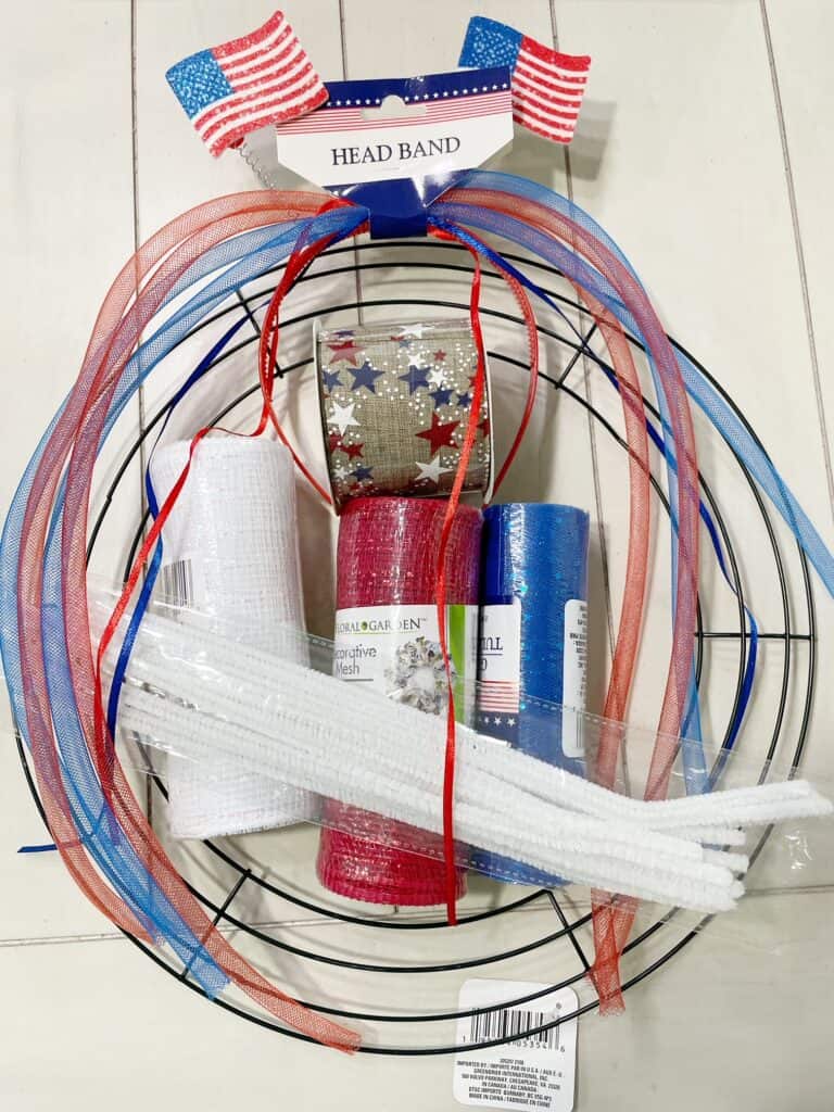 A wire wreath form, red deco mesh, white deco mesh, blue deco mesh, pipe cleaners, ribbon and Patriotic head band.