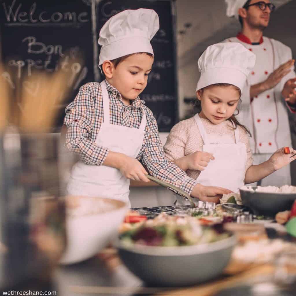 Young boy and girl in aprons and chefs hats at a cooking class.