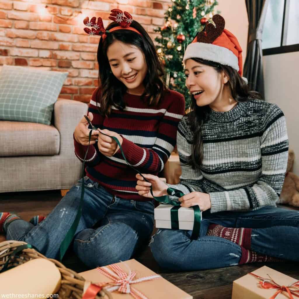 Two women helping each other wrap  Christmas gifts.