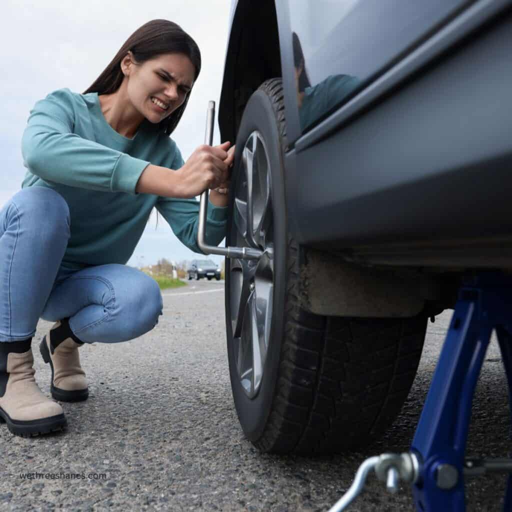 Young woman trying to fix a flat tire on a car