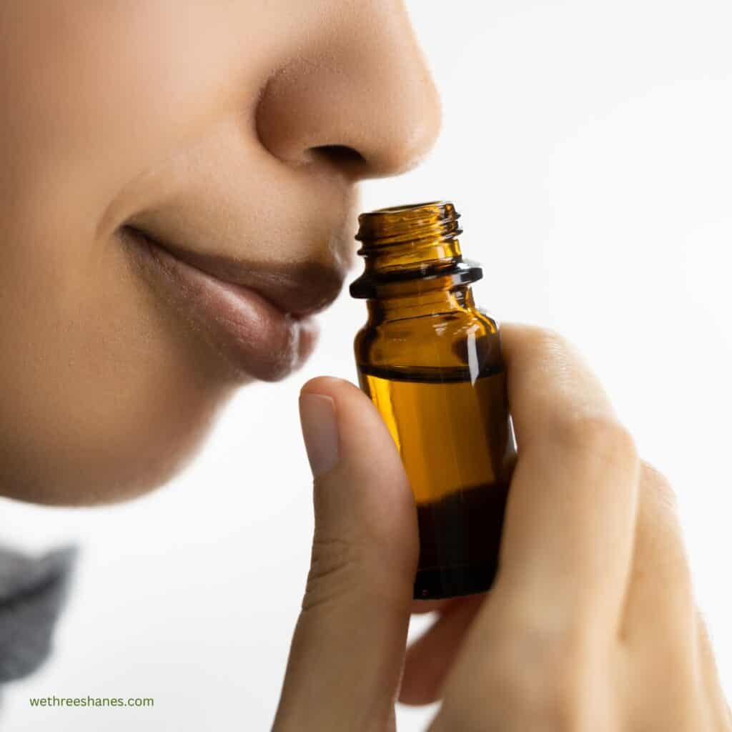 close up of a women smell a glass bottle of essential oils.
